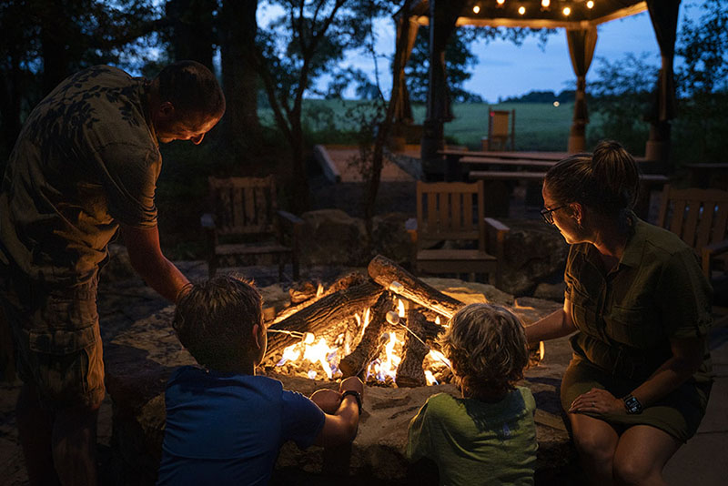 Two adults and two children roast marshmallows over a firepit.